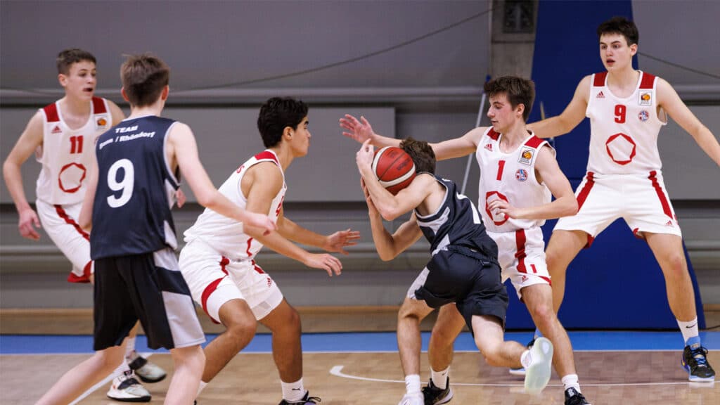 Basketballspiel der RheinStars Köln: Spieler in weißen und dunkelblauen Trikots kämpfen um den Ball in der Halle.