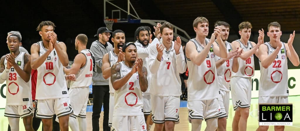 RheinStars-Köln-Basketballteam applaudiert gemeinsam in weißen Trikots in der Sporthalle.