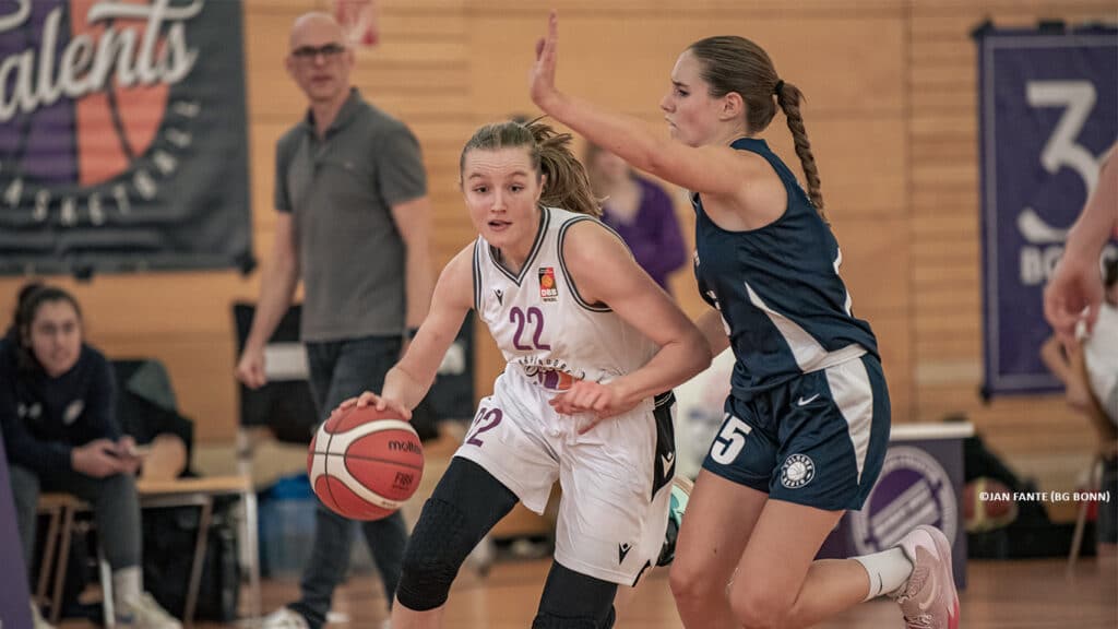Basketballspielerin der RheinStars Köln dribbelt den Ball während eines Spiels gegen gegnerische Defensivspielerin.