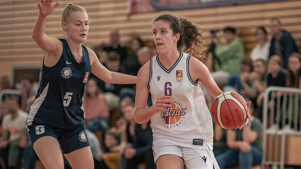 Basketballspiel der RheinStars Köln: Spielerin Nummer 6 dribbelt den Ball, während eine Verteidigerin der gegnerischen Mannschaft sie deckt.