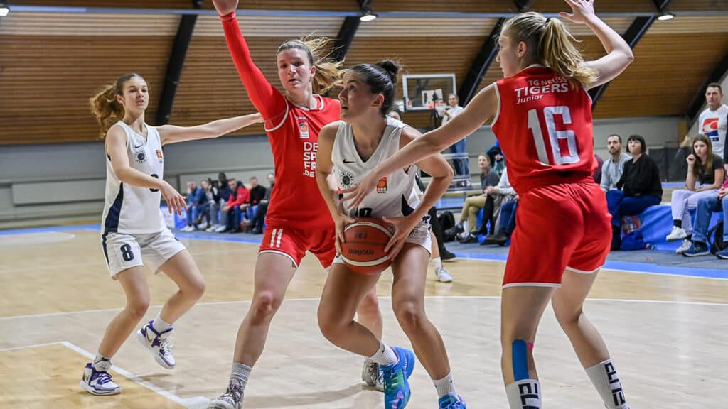 Basketballspiel der RheinStars Köln gegen TG Neuss Tigers in einer Sporthalle mit Zuschauern.