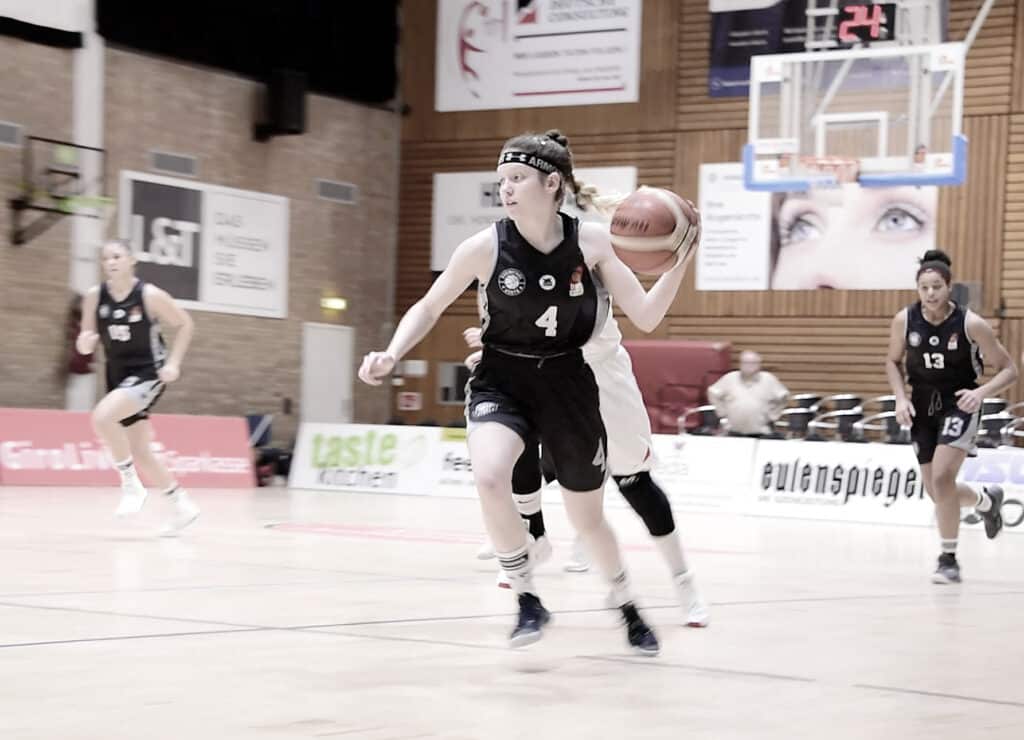 Basketballspielerin der RheinStars Köln mit Nummer 4 dribbelt den Ball in der Sporthalle.