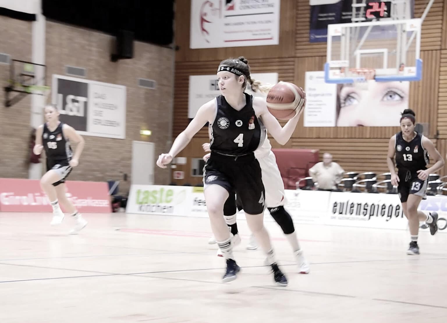Basketballspielerin der RheinStars Köln mit Nummer 4 dribbelt den Ball in der Sporthalle.