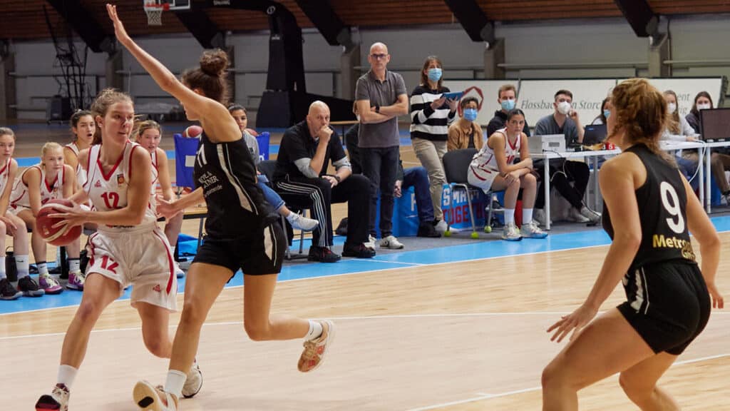 Basketballspiel der RheinStars Köln: Spielerin in weißem Trikot dribbelt gegen Verteidigerin in schwarzem Trikot.