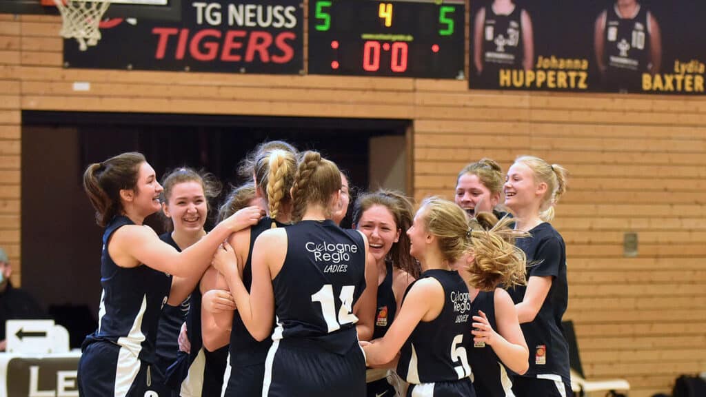 Damenbasketballteam der RheinStars Köln jubelt zusammen in der Sporthalle.