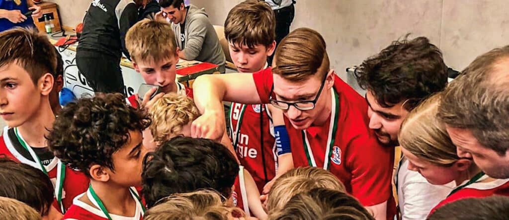 Jugendliche der RheinStars Köln feiern gemeinsam einen Sieg mit Medaillen.