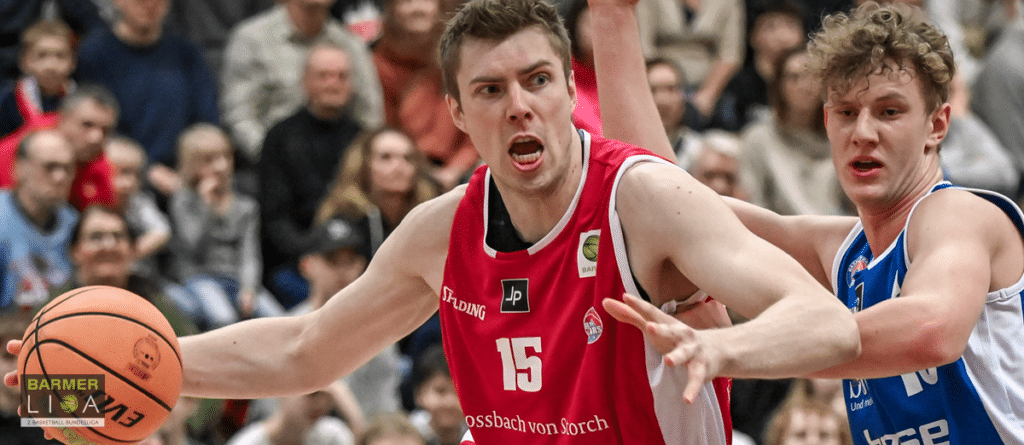 Basketballspieler der RheinStars Köln in rotem Trikot Nummer 15 dribbelt Ball während Spielszene.