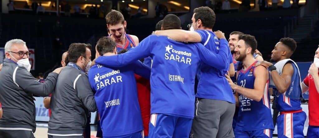 Basketballteam in blauen Trikots feiert zusammen nach Spielende.