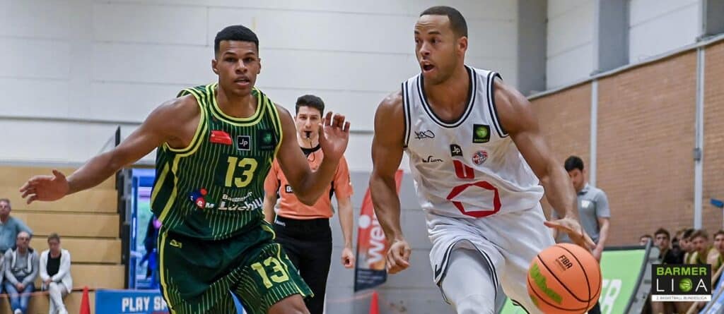 Basketballspiel der RheinStars Köln: Spieler in weißem Trikot dribbelt gegen Gegner in grün-gelbem Trikot.