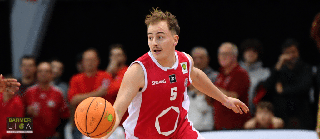 Basketballspieler der RheinStars Köln in rotem Trikot mit Nummer 5 dribbelt den Ball.