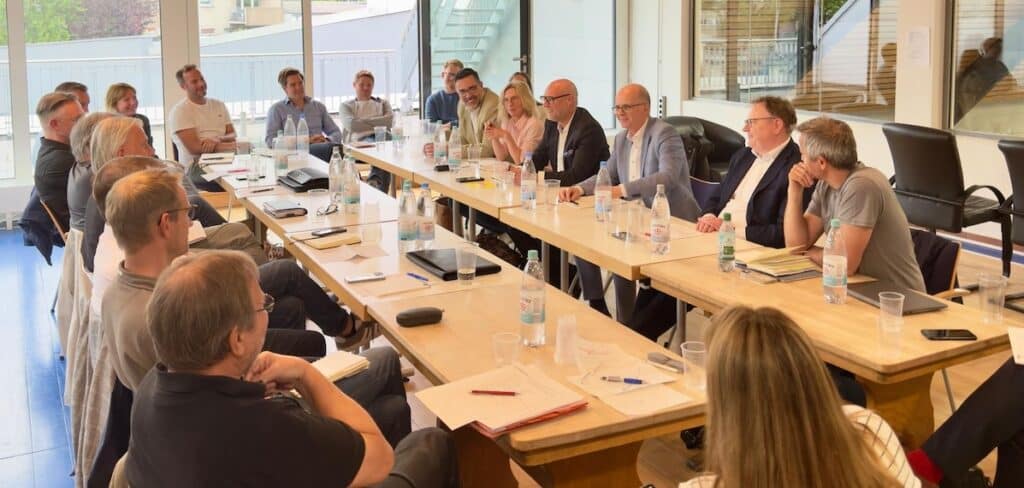 Geschäftstreffen der RheinStars Köln in modernem Konferenzraum mit etwa 20 Teilnehmern an langer Holztafel.