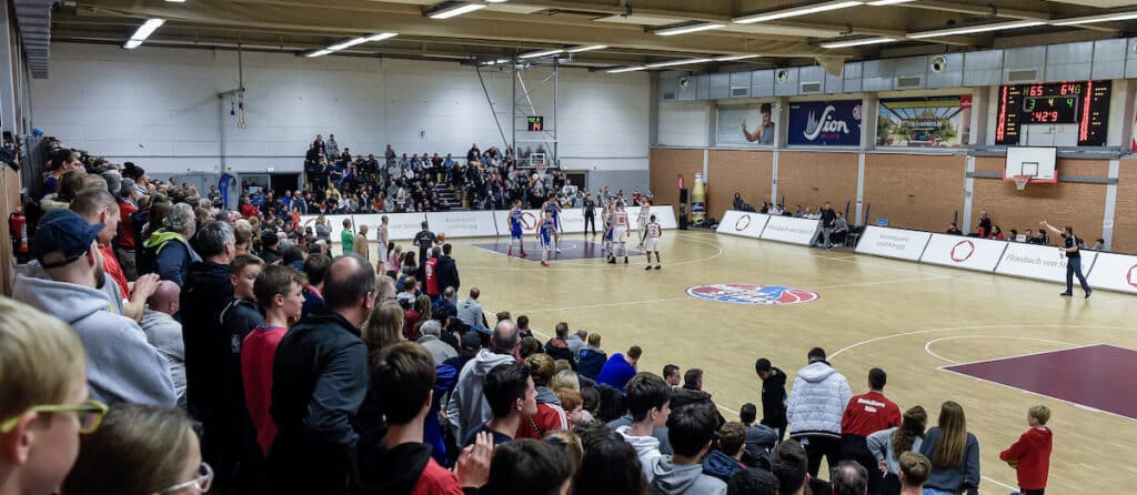 Zuschauer verfolgen ein Basketballspiel der RheinStars Köln in einer Sporthalle.