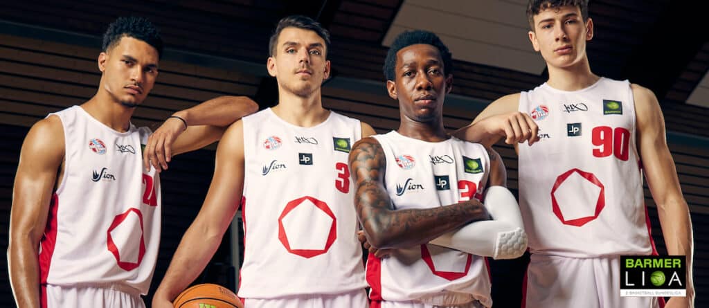 Vier Basketballspieler der RheinStars Köln posieren in weißen Trikots mit rotem Logo.