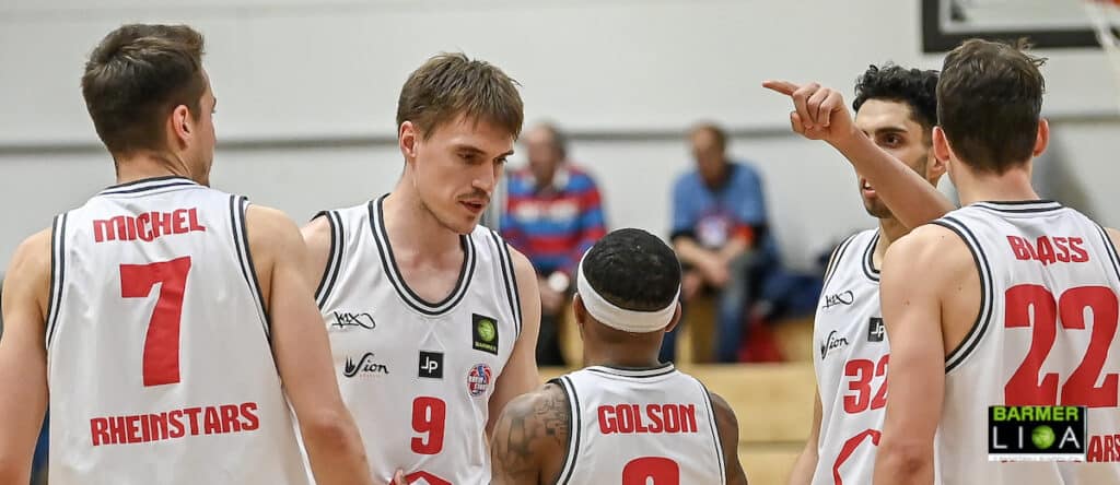 Basketballteam der RheinStars Köln in weißen Trikots beim Spielzusammenhalt.