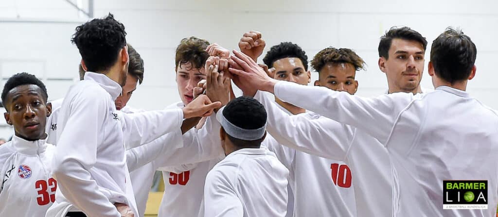 Basketballteam RheinStars Köln im Mannschaftskreis bei Teamritual mit verschränkten Armen.