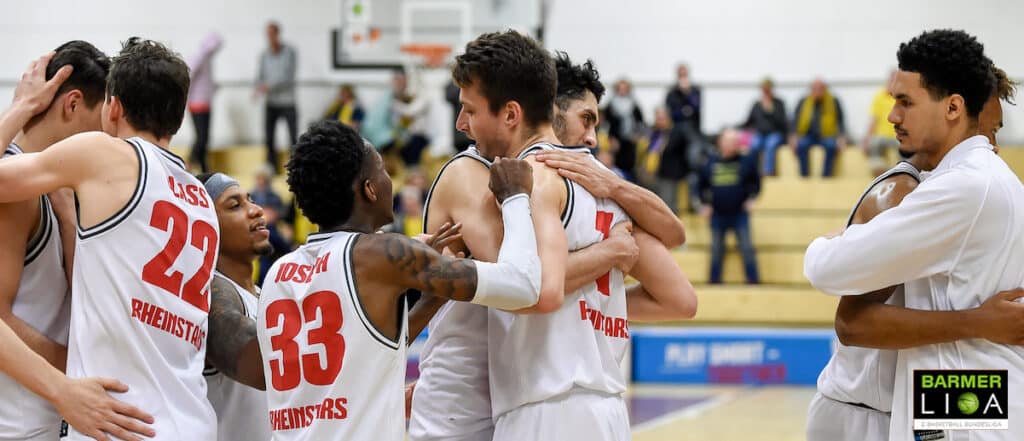 Basketballteam RheinStars Köln steht zusammen und motiviert sich gegenseitig während eines Spiels in der Halle.