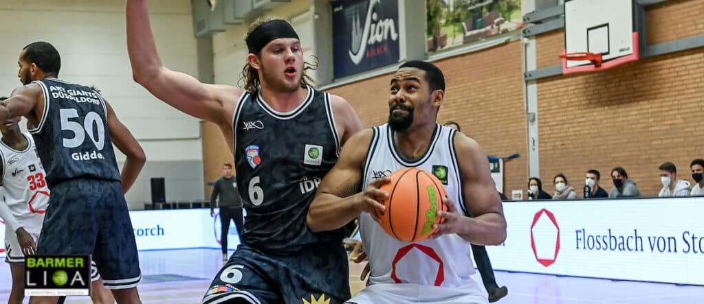 Basketballspiel der RheinStars Köln: Spieler in weißem Trikot mit Ball gegen Verteidiger in schwarzem Trikot Nummer 6.