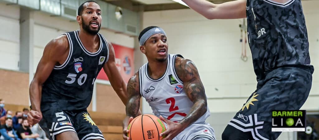 Basketballspiel der RheinStars Köln: Spieler in weißem Trikot mit Nummer 2 dribbelt gegen Gegner in schwarzem Trikot mit Nummer 50.