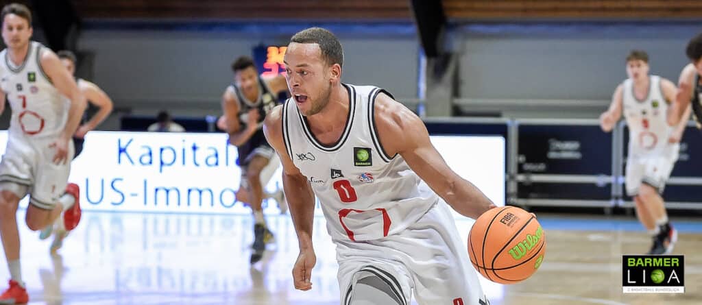Basketballspieler der RheinStars Köln dribelt den Ball in weißem Heimtrikot.