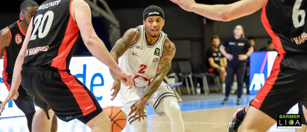 Basketballspieler der RheinStars Köln in Nummer 2 dribbelt gegen gegnerische Spieler in schwarzem Trikot.