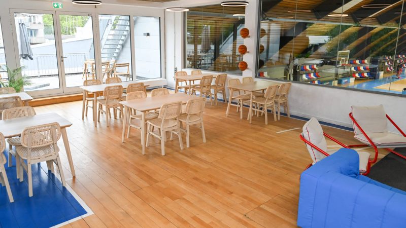 Campus der RheinStars Köln mit Holzparkett, Tischen, Stühlen und Sportausstattung.