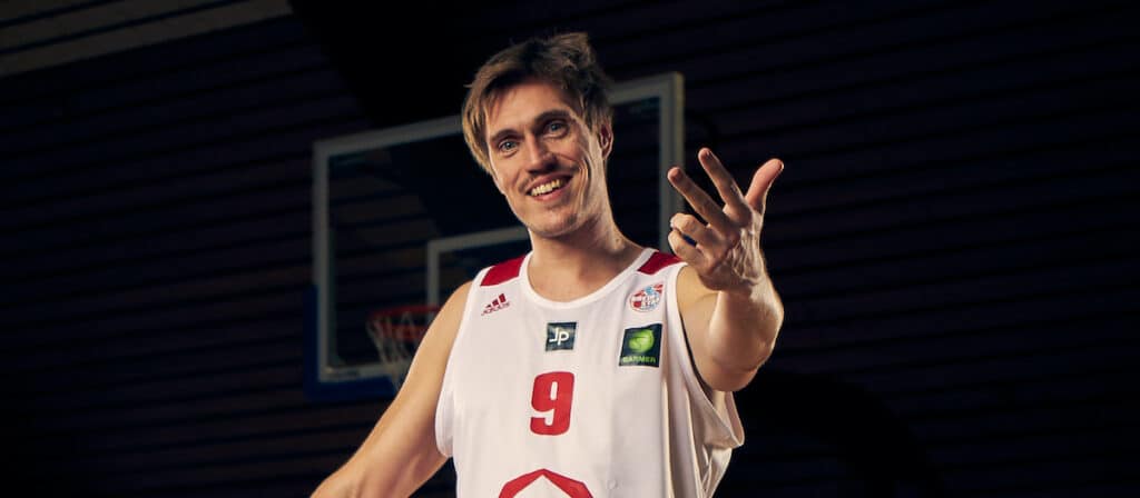 Basketballspieler der RheinStars Köln in Nummer 9 Trikot zeigt Friedenszeichen.