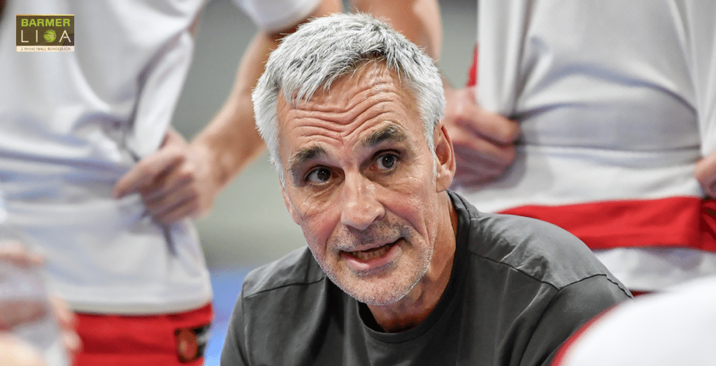 Mann mittleren Alters mit grauem Haar spricht in einer Trainingshalle der RheinStars Köln.