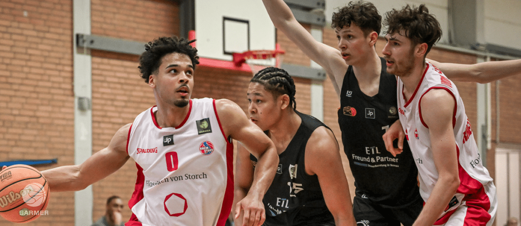 Basketballspiel der RheinStars Köln in weißem Heimtrikot gegen schwarzes Auswärtsteam in der Sporthalle.