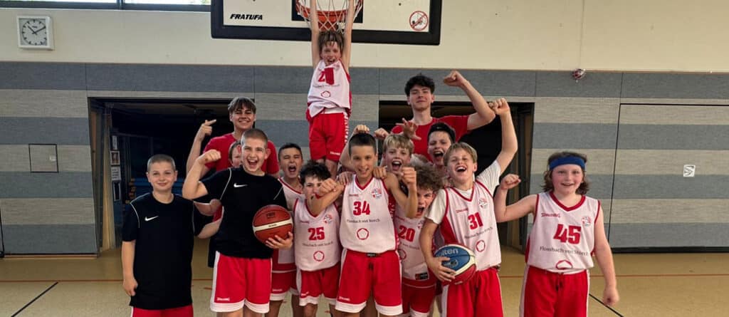 Basketballmannschaft RheinStars Köln feiert gemeinsam in der Sporthalle.