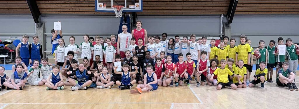 Große Gruppe von Kindern und Jugendlichen der RheinStars Köln in einer Sporthalle, posierend für ein Teamfoto.