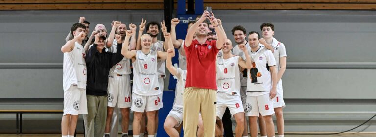 Eine Basketballmannschaft der RheinStars Köln jubelt gemeinsam in einer Sporthalle.