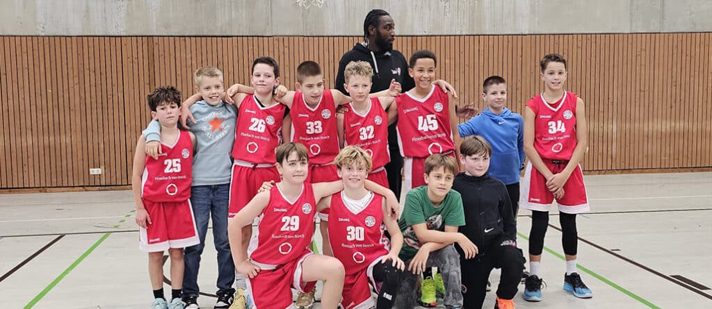 Kinder-Basketballteam RheinStars Köln posiert in Sporthalle.