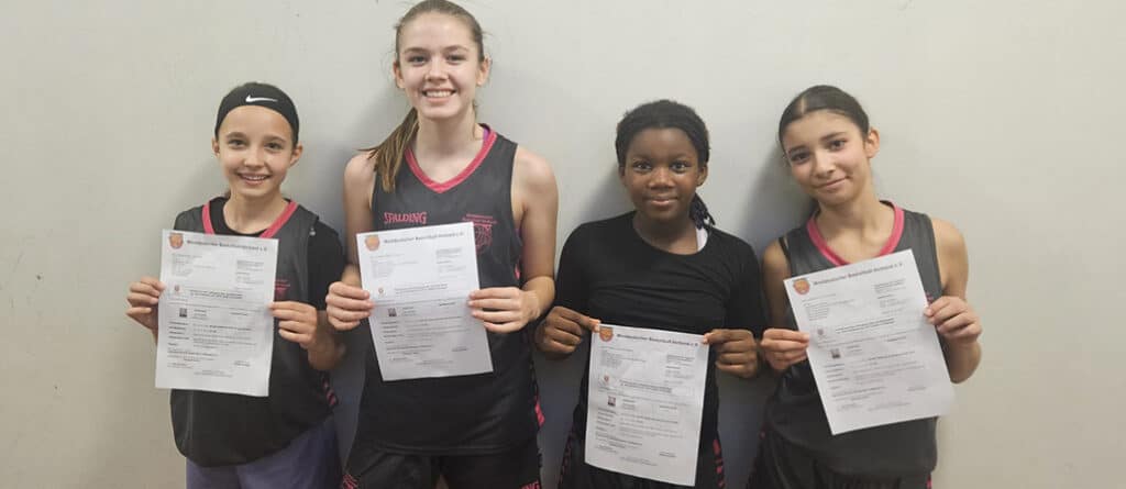 Vier junge Basketballerinnen der RheinStars Köln halten stolz ihre Urkunden in die Kamera.