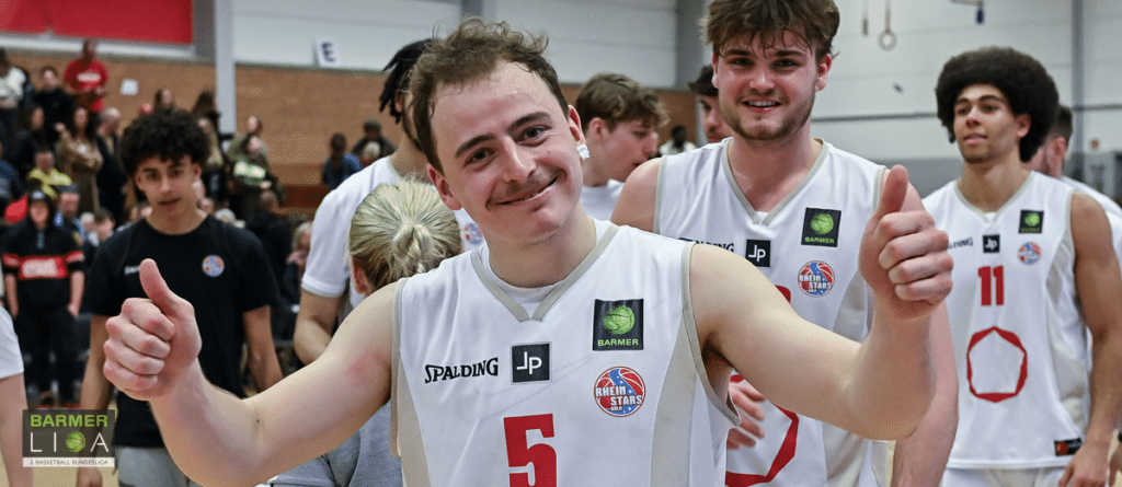 Basketballspieler der RheinStars Köln zeigen Daumen hoch nach dem Spiel in der Halle.