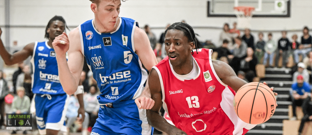 Basketballspiel der RheinStars Köln: Spielerin in rotem Trikot mit Ball gegen Gegner in blauem Trikot.