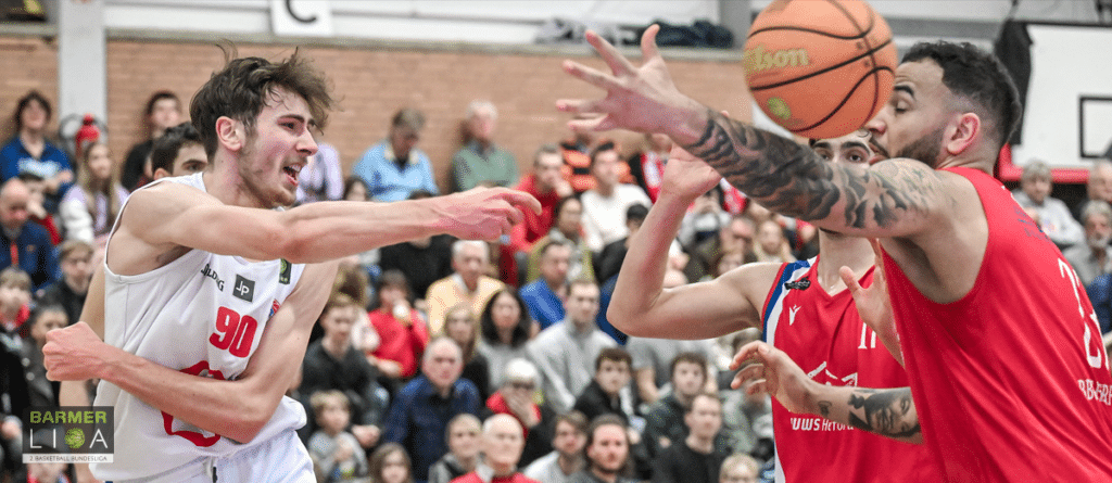 Basketballspiel der RheinStars Köln: Spieler in Weiß verteidigt gegen Spieler in Rot mit Ball.