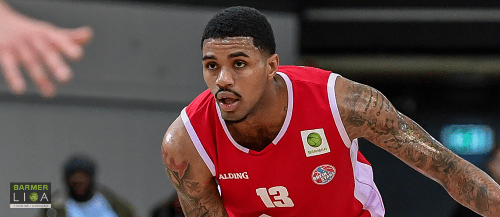 Basketballspieler der RheinStars Köln mit Nummer 13 in rotem Trikot während eines Spiels.
