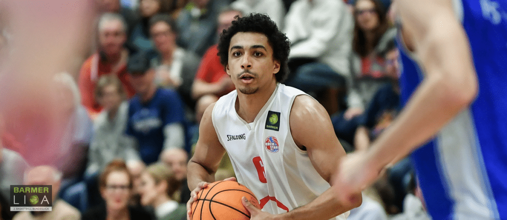 Basketballspieler der RheinStars Köln mit Nummer 1 im weißen Trikot mit Ball.