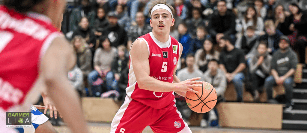 Basketballspieler der RheinStars Köln in rotem Trikot mit Nummer 5 dribbelt während eines Spiels.