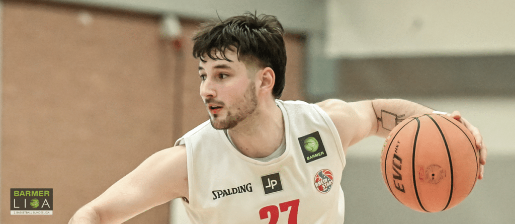 Basketballspieler der RheinStars Köln mit Nummer 27 dribbelt den Ball in der Sporthalle.