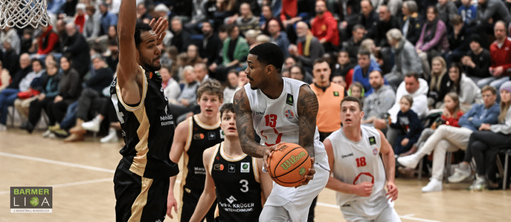 Basketballspiel der RheinStars Köln: Spieler in weißem Trikot mit Nummer 15 dribbelt gegen Verteidiger in schwarzem Trikot.