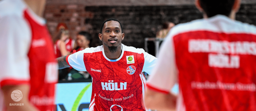 Basketballspieler der RheinStars Köln in rotem Trikot während eines Spiels.