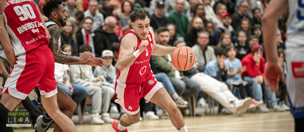 RheinStars-Köln-Spieler dribbelt mit Basketball während Heimspiel vor Zuschauern.