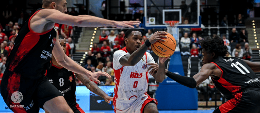 Basketballspieler der RheinStars Köln dribbelt Ball zwischen zwei Verteidigern.