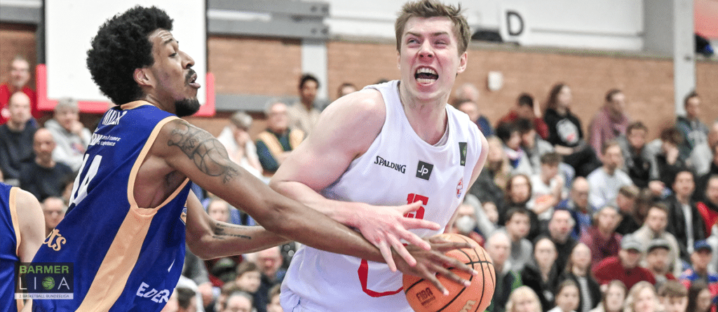 Basketballspiel der RheinStars Köln: Spieler in Weiß dribbelt gegen Gegner in Blau.