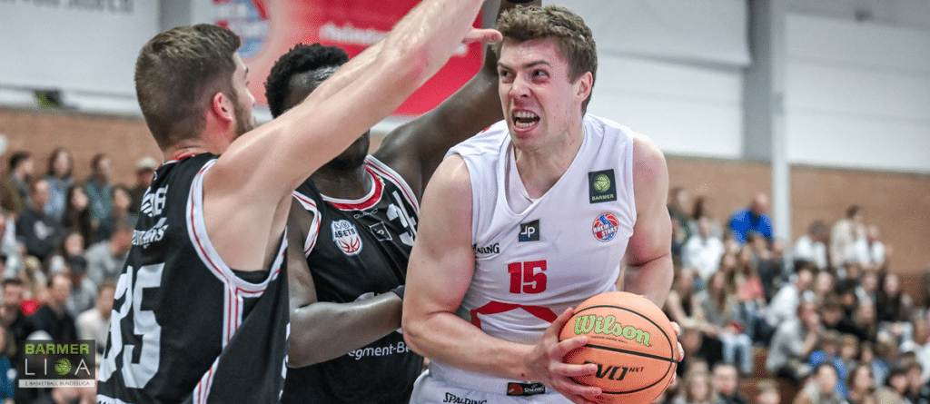 Basketballspieler der RheinStars Köln in weißem Trikot mit Nummer 15 hält einen Wilson-Basketball während eines Spiels in der Halle.