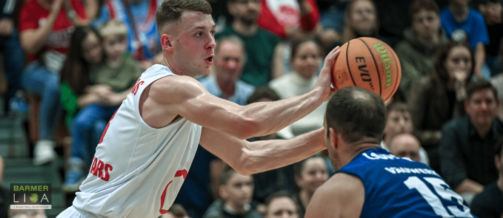 Basketballspieler der RheinStars Köln im weißen Trikot passt den Ball während eines Spiels.