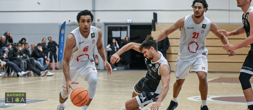 Basketballspiel der RheinStars Köln: Spieler in weißem Trikot dribbelt gegen Gegner in schwarzem Trikot.
