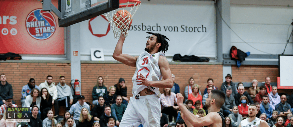Basketballspieler der RheinStars Köln beim Dunking vor Publikum in der Sporthalle.