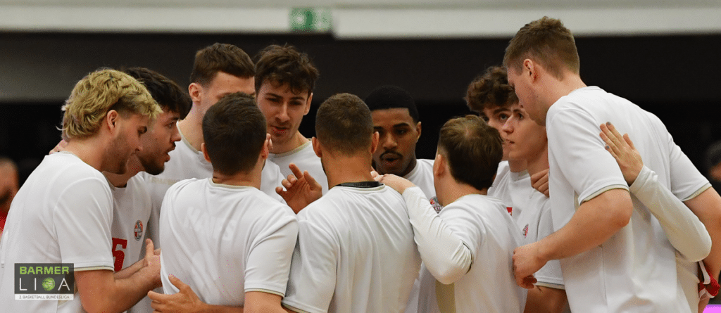 Basketballmannschaft RheinStars Köln in Huddle-Formation mit verschränkten Armen.